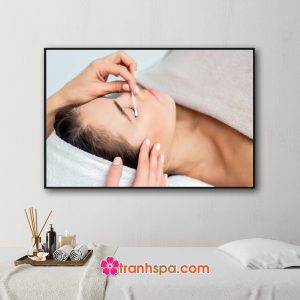 Mẫu tranh trang trí spa đẹp hình ảnh khách hàng nữ đang được chăm sóc da và làm đẹp vùng mặt