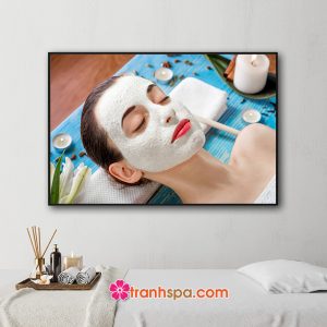 Mẫu tranh trang trí spa đẹp hình ảnh nữ khách hàng được đắp mặt nạ chăm sóc da với hoa và nến thơm xung quanh