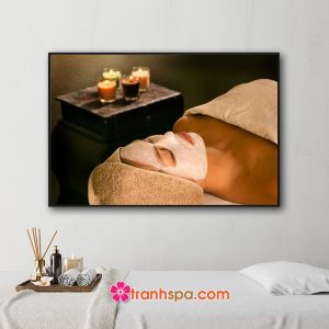 Mẫu tranh treo spa đẹp hình ảnh cô gái đắp mặt nạ chăm sóc da trong phòng có ánh sáng ấm áp của những ngọn nến thơm