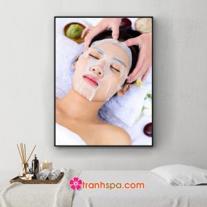 Mẫu tranh treo spa đẹp hình ảnh khách hàng nữ nằm thư giãn khi được đắp mặt nạ dưỡng da và nhân viên thẩm mỹ viên massage vùng đầu