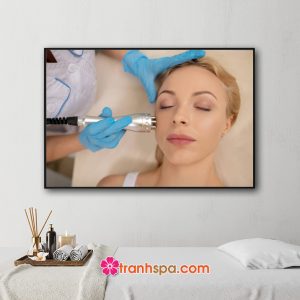 Mẫu tranh treo spa đẹp hình ảnh nhân viên thẩm mỹ viện sử dụng thiết bị công nghệ để chăm sóc làm đẹp da mặt cho khách hàng