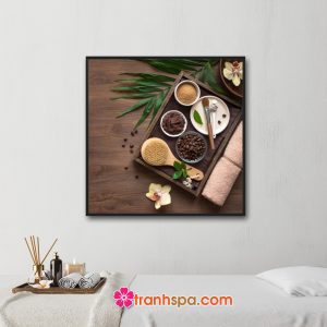 Mẫu tranh trang trí spa đẹp khổ vuông hình ảnh hạt và bột cafe, hoa lan, khăn tắm, dụng cụ làm đẹp đặt trên nền gỗ màu nâu trầm