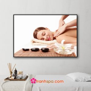 Mẫu tranh trang trí spa đẹp hình ảnh nữ khách hàng đang được massage thư giãn vai lưng bên cạnh là đá cuội và hoa ly trong bát nước tinh khiết