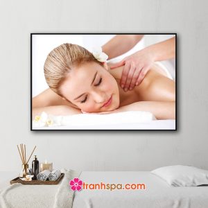 Mẫu tranh treo spa đẹp hình ảnh nhân viên đang massage vai cho nữ khách hàng với hoa lan trắng cài trên tóc