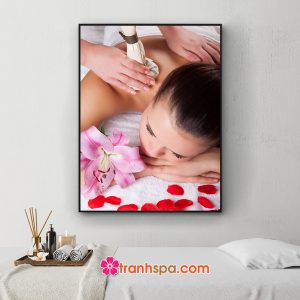 Mẫu tranh trang trí spa đẹp hình ảnh nữ khách hàng đang được nhân viên dùng túi chườm massage thư giãn với hoa ly và cánh hồng trang trí xung quanh