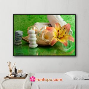 Mẫu tranh trang trí spa đẹp hình ảnh những viên đá xếp chồng, khay nến thơm, hoa ly và khăn tắm đặt trên nền màu xanh lục loang đẹp