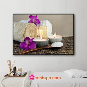 Mẫu tranh trang trí spa đẹp hình ảnh khăn tắm cuộn tròn, những bông hoa lan tím, tinh dầu, muối tắm và nến thơm đặt trên mành trúc màu nâu đen trầm ấm