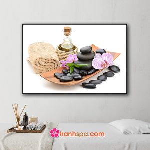 Mẫu tranh trang trí spa đẹp hình ảnh khăn cuộn, chai tinh dầu và khay gỗ chứa đá cuội và hoa lan tím
