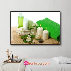 Mẫu tranh trang trí spa đẹp hình ảnh giỏ mỹ phẩm làm đẹp, nến thơm, khăn tắm xanh và những cành hoa đặt trên tấm mành trúc