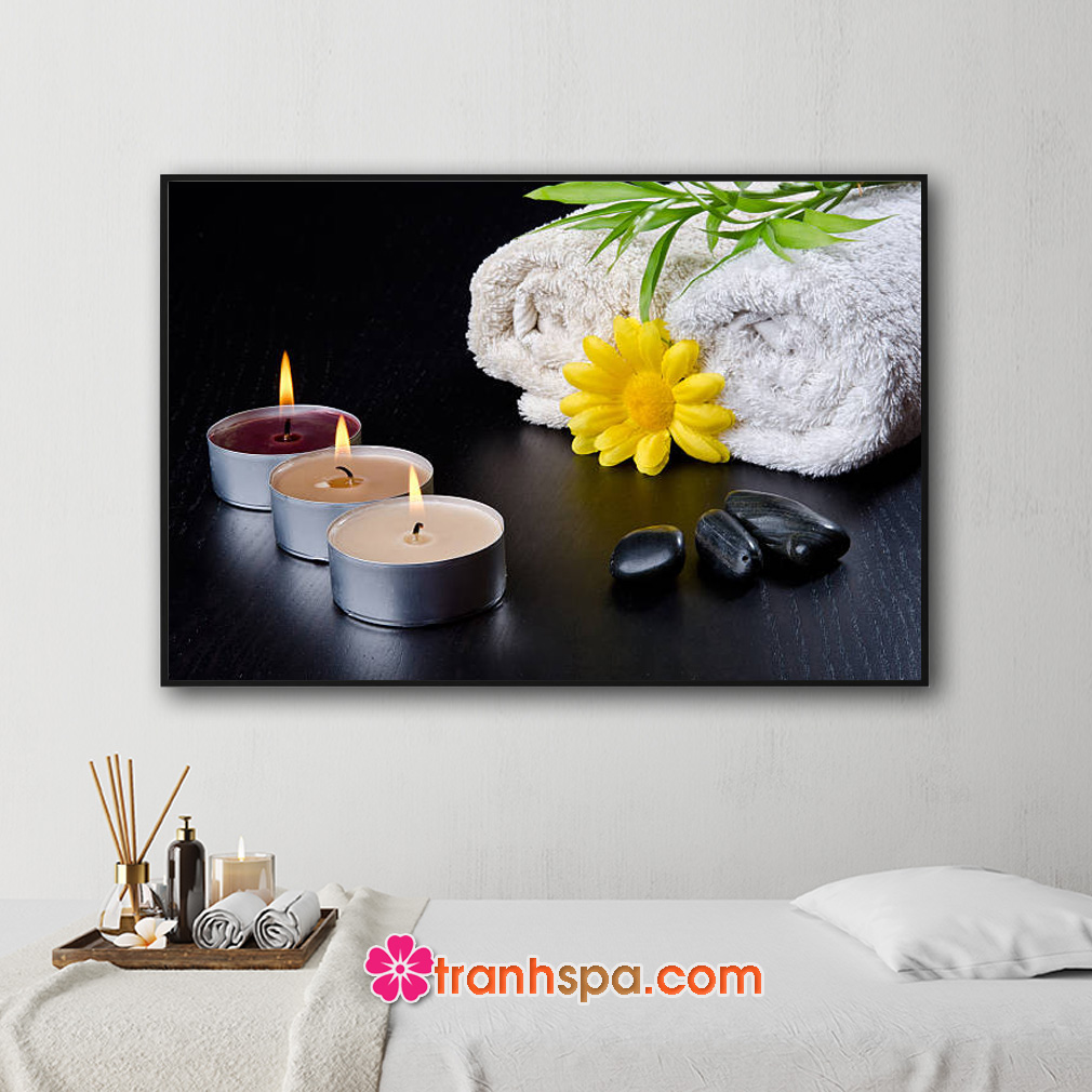 Mẫu tranh trang trí spa đẹp hình ảnh khăn tắm, cành lộc xanh, hoa hướng dương vàng, những ngọn nến thơm và đá cuội đặt trên mặt sàn gỗ sơn đen