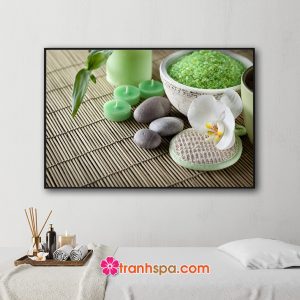 Mẫu tranh trang trí spa đẹp hình ảnh cành lộc xanh, hoa lan trắng, muối tắm xanh, nến thơm xanh và những viên đá cuội đặt trên tấm mành trúc