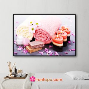 Mẫu tranh trang trí spa đẹp hình ảnh những cuộn khăn tắm màu vàng kem và hồng, nến thơm nhiều màu, soap và kem dưỡng da, hoa cúc trắng và những cánh hoa màu tím