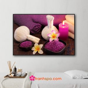Mẫu tranh trang trí spa đẹp hình ảnh khăn tắm, túi chườm, nến thơm, muối tắm và hoa sứ đặt trên nền mành tre với 2 gam màu tím và trắng đẹp