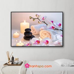 Mẫu tranh trang trí spa đẹp hình ảnh những cành hoa lan, khăn tắm, đá cuội đen và nến thơm cháy sáng lung linh