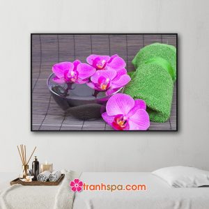 Mẫu tranh trang trí spa đẹp hình ảnh cuộn khăn tắm màu xanh, những bông hoa lan tím trên chậu nước tinh khiết đặt trên mành trúc màu nâu trầm
