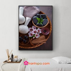 Mẫu tranh spa khổ dọc đẹp hình ảnh chiếc khay mây đan chứa khăn tắm, túi chườm, đá cuội, hoa...đặt trên nền màu nâu xám trầm ấm